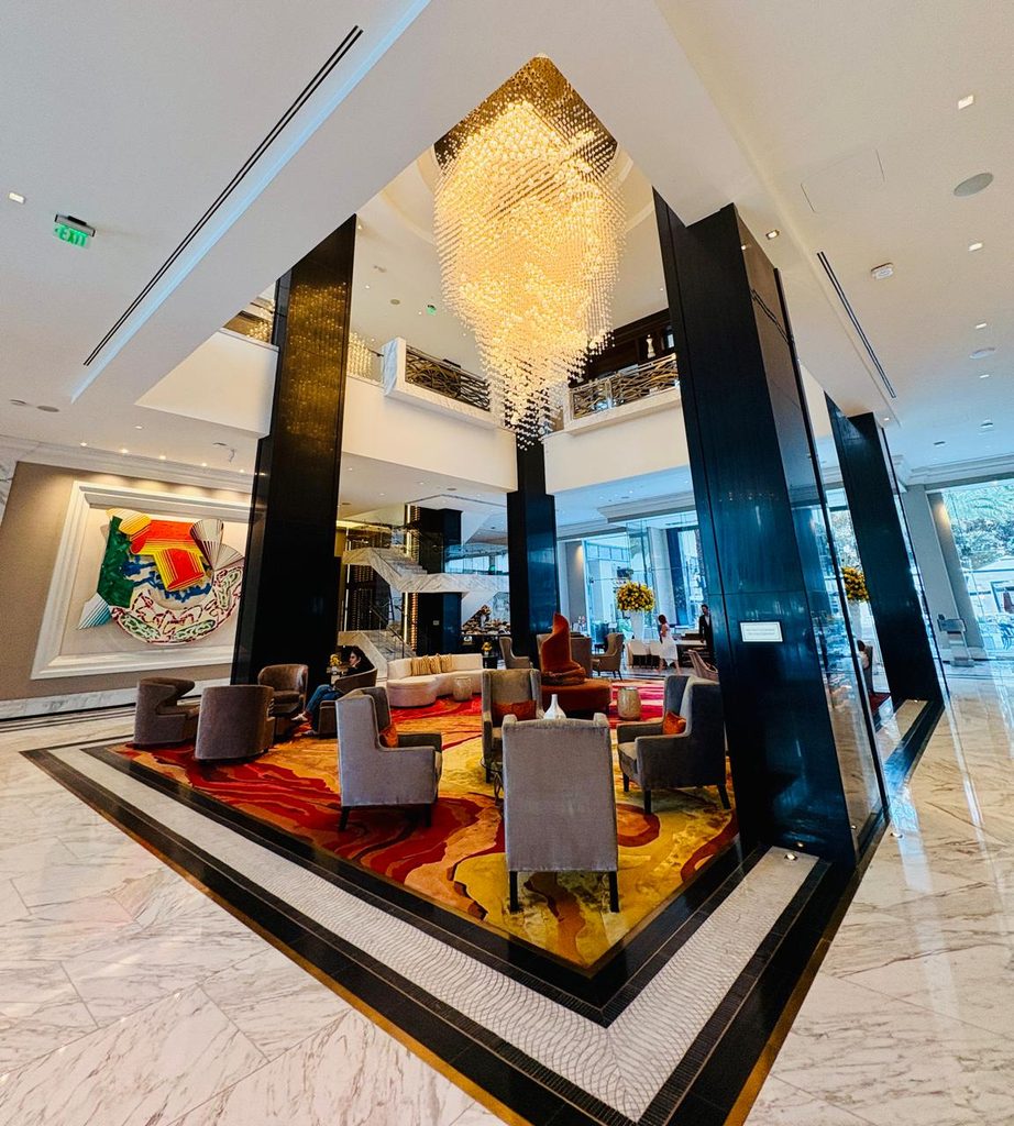 lobby of an upscale hotel with a large colorful artwork on the wall, black marble columns 