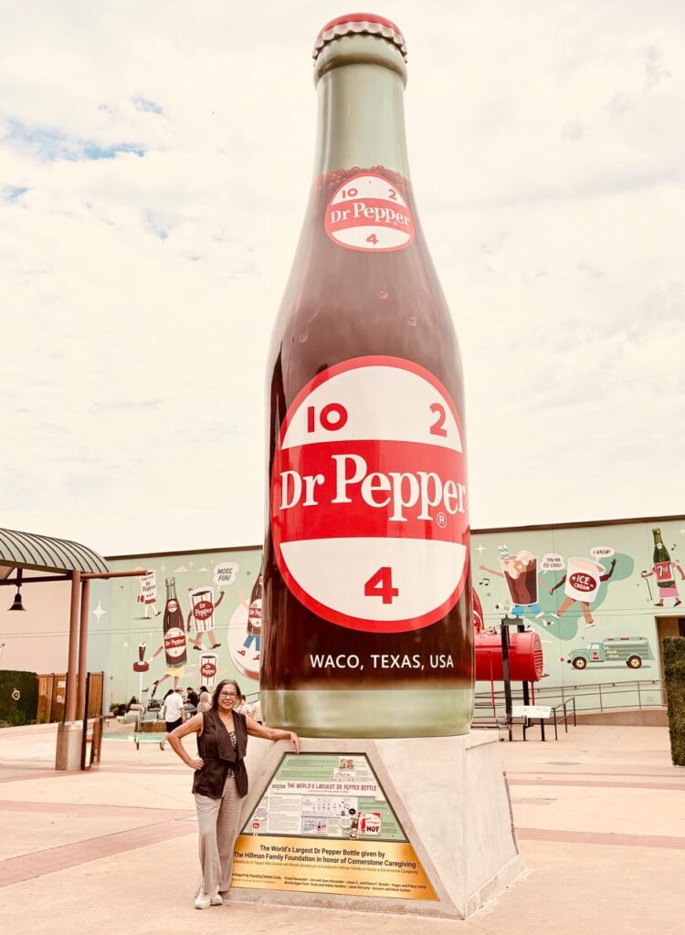 woman standing by the Dr. Pepper bottle Dr. Pepper museum